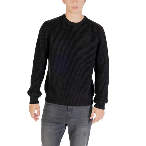 Black ribbed crew neck sweater with long sleeves and a relaxed fit.
