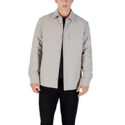 Men’s light grey collared shirt with chest pocket worn open over black t-shirt and pants