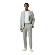 Antony Morato Grauer Herrenblazer aus Polyester mit V-Ausschnitt und Revers, kombiniert mit einer eleganten, hellgrauen Stoffhose mit Kordelzug und weißen Sneakers.