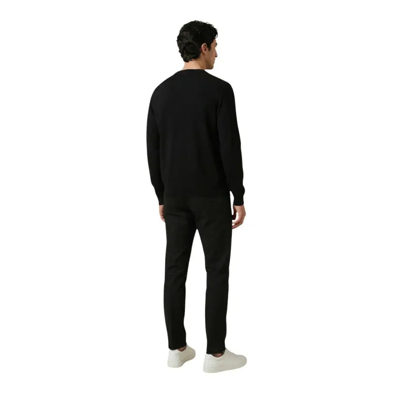 Antony Morato Herrenhose kombiniert mit einem schwarzen Rundhalspullover mit langen Ärmeln und einer glatten, figurbetonten Silhouette