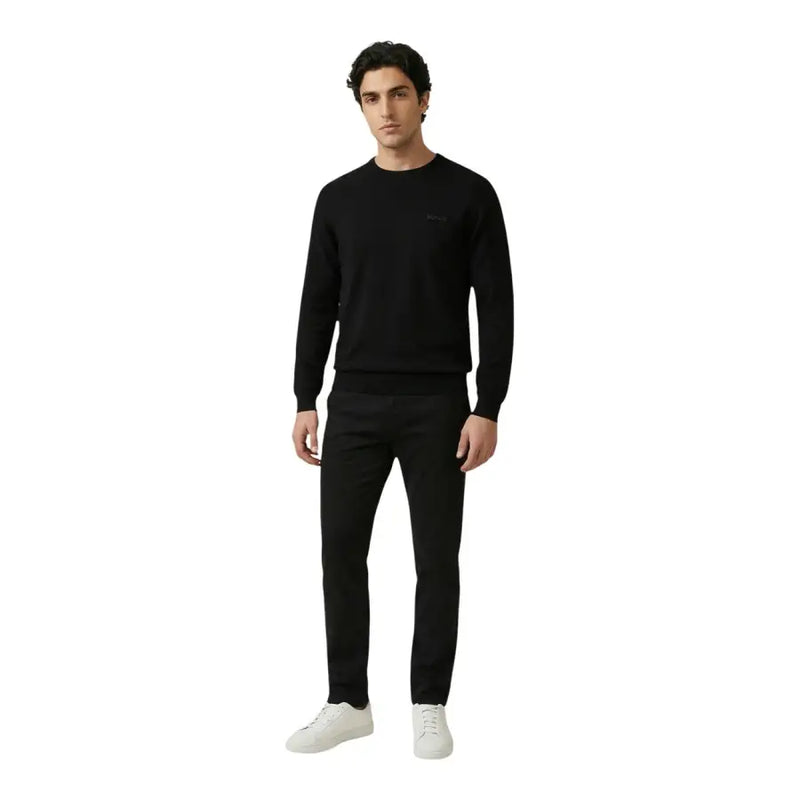Antony Morato Herrenhose kombiniert mit einem schwarzen Strickpullover mit dezentem, gesticktem Logo auf der linken Brust.