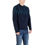 Marineblauer Pullover mit grünem Zickzackmuster, wahrscheinlich aus einem Woll- oder Baumwollmischgewebe.