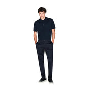 Ein Mann, der einen Armani Exchange Herren-Poloshirt aus blauer Baumwolle mit kurzen Ärmeln und dezentem, gesticktem Logo auf der Brust