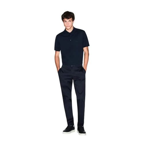 Ein Mann, der einen Armani Exchange Herren-Poloshirt aus blauer Baumwolle mit kurzen Ärmeln und dezentem, gesticktem Logo auf der Brust