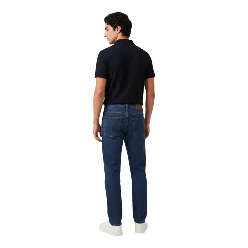 Dunkelblaue Jeans mit fünf Taschen und braunem Lederpatch, kombiniert mit armani exchange blaues Herren-Polohemd mit Reißverschluss