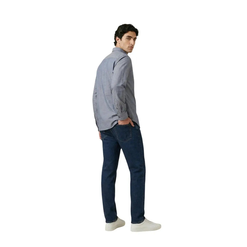 A man wearing an Armani Exchange men shirt in light gray button-up cotton paired with dark blue jeans