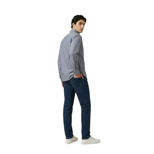 A man wearing an Armani Exchange men shirt in light gray button-up cotton paired with dark blue jeans