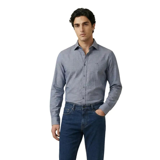 A man wearing an Armani Exchange gray textured long-sleeve button-down shirt with subtle pattern and embroidered logo