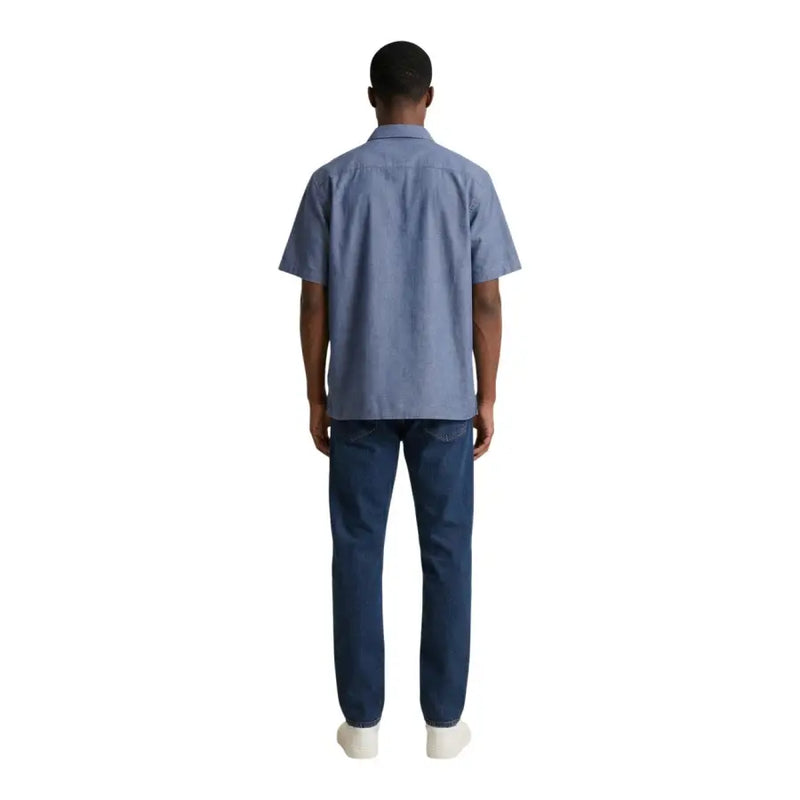 Ein Mann, der einen armani exchange hellblaues, kurzärmeliges Baumwollhemd und dunkelblaue Jeans