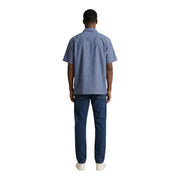 A man wearing an armani exchange light blue short-sleeved cotton shirt and dark wash denim jeans