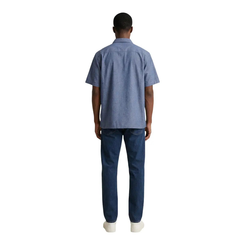 A man wearing an armani exchange light blue short-sleeved cotton shirt and dark wash denim jeans