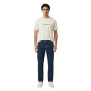 Ein Mann, der einen Armani Exchange Creme t-shirt mit goldenem Maison Margiela Logo und dunkelblauen Jeans