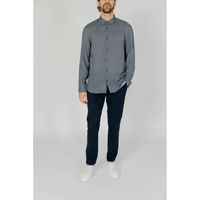 A man wearing an Armani Exchange men’s classic grey long sleeve button-down shirt with a white geometric pattern