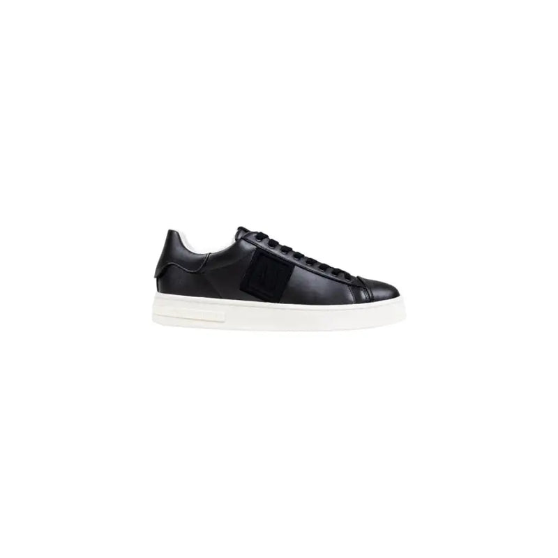 Black leather low-top sneaker with white sole and strap detail.