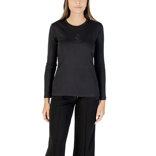 Woman wearing a black long-sleeved crew-neck top and black track pants, showcasing Armani Exchange T-shirt