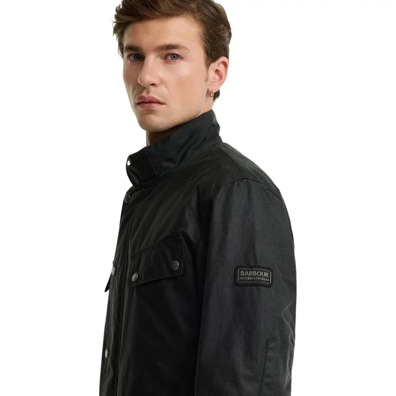Barbour International Herren-Wachsjacke aus schwarzer Baumwolle mit matter Oberfläche und geknöpften Pattentaschen.