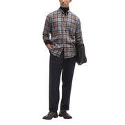 Ein Mann trägt ein Barbour-Herrenhemd in braun-grau-beigem Karomuster mit schwarzen Manschetten und Knopfleiste.