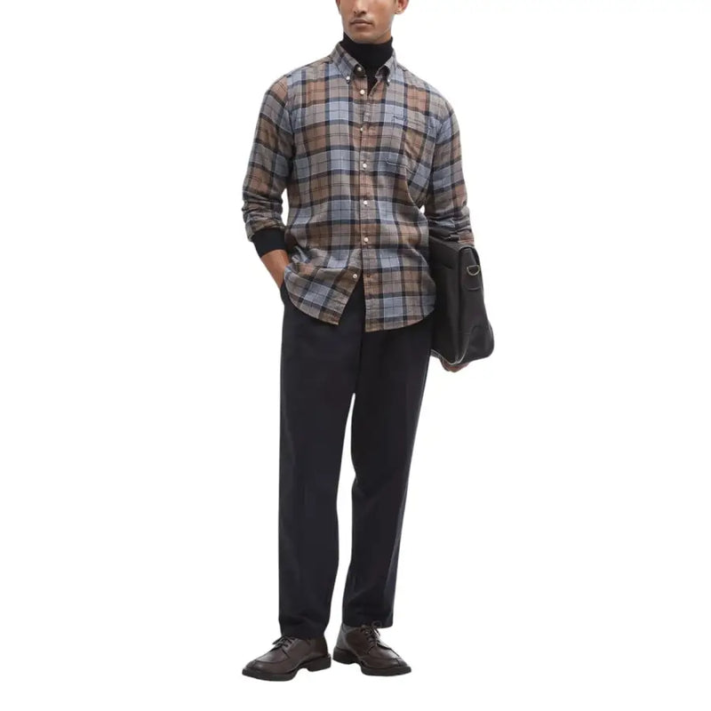 Ein Mann trägt ein Barbour-Herrenhemd in braun-grau-beigem Karomuster mit schwarzen Manschetten und Knopfleiste.