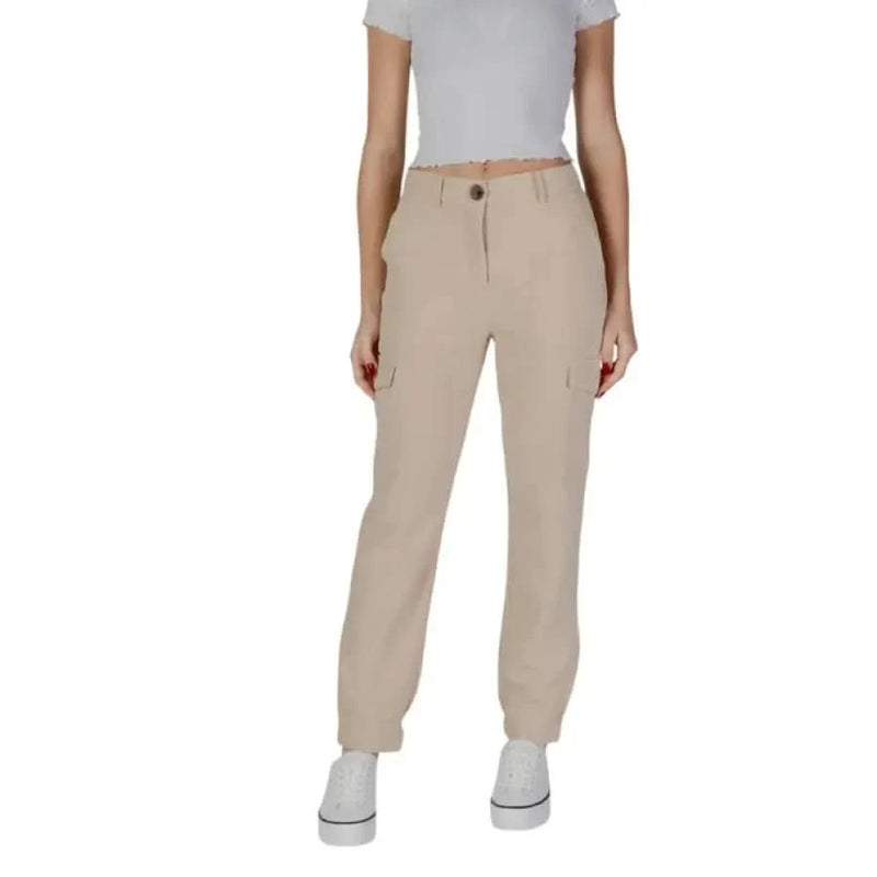 Beige cargo pants with pockets styled with a white crop top and white sneakers