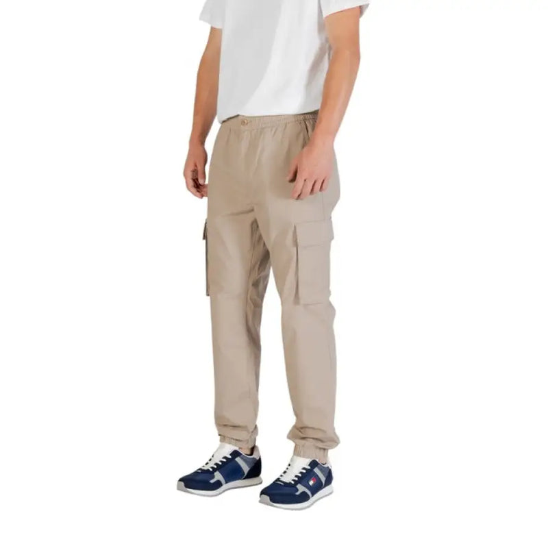 Beige cargo pants with multiple pockets displayed on a clothing rack