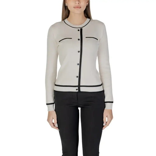 Beige long sleeve knit cardigan with front pockets made of cream-colored knit with black trim on neckline and cuffs