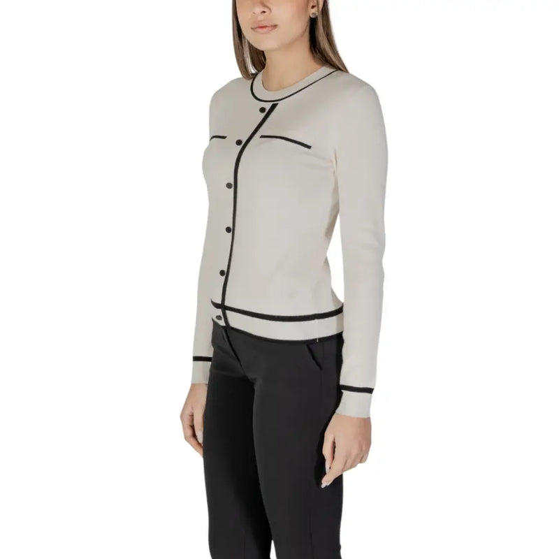 Beige long sleeve knit cardigan with front pockets in off-white with black trim on neckline button placket and cuffs