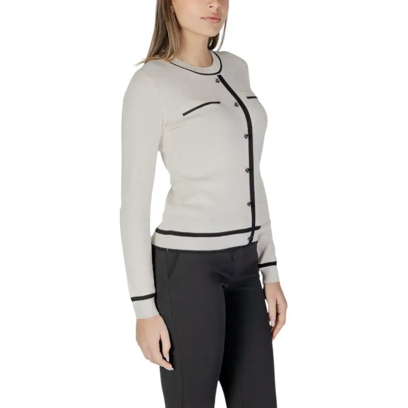 Beige long sleeve knit cardigan in off-white with black trim featuring front pockets and a sleek design