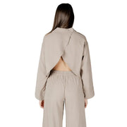 Beige viscose long sleeve round neck cropped blouse for women with a distinctive back cutout shown from the back side
