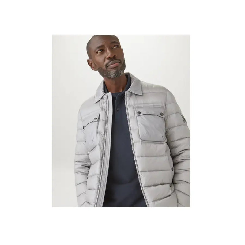 Belstaff Herren-Polohemd aus Baumwolle mit langen Ärmeln in Blau, kombiniert mit einer hellgrauen Steppjacke mit Stehkragen und Pattentaschen.