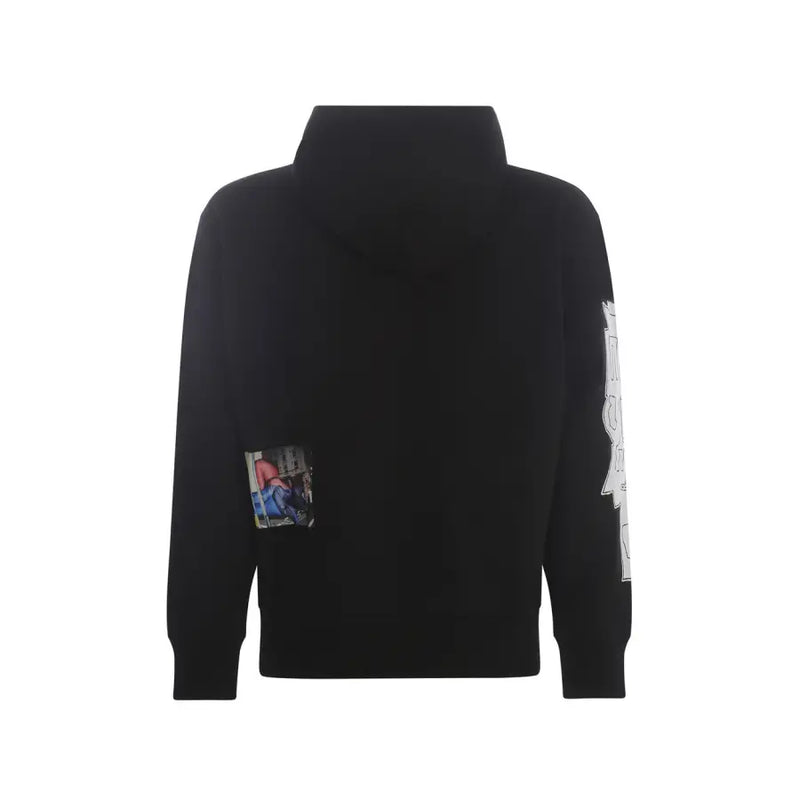 Schwarzer Kapuzenpullover mit kleinem rechteckigem Fotoaufnäher auf der linken Brust und weißem Grafikdesign auf dem rechten Ärmel