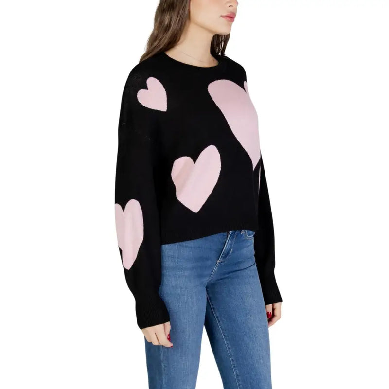 Black long sleeve round neck viscose knit top for women with pink heart patches on a black knit sweater