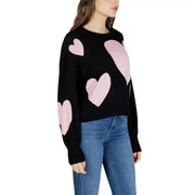 Black long sleeve round neck viscose knit top for women with pink heart patches on a black knit sweater