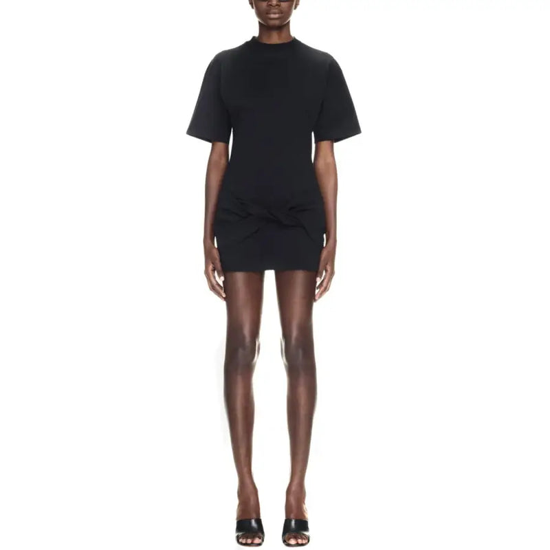 Black short-sleeved mini dress with high neckline and gathered waist detail paired with sculptural heels