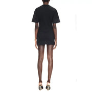 Black short-sleeved mini dress with a simple fitted silhouette paired with sculptural heels and knotted detail
