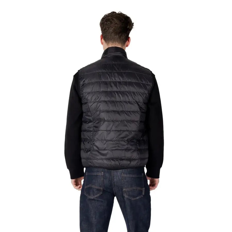 Black quilted vest with knit sleeves featuring a high collar and sleeveless design in a sleek puffer style