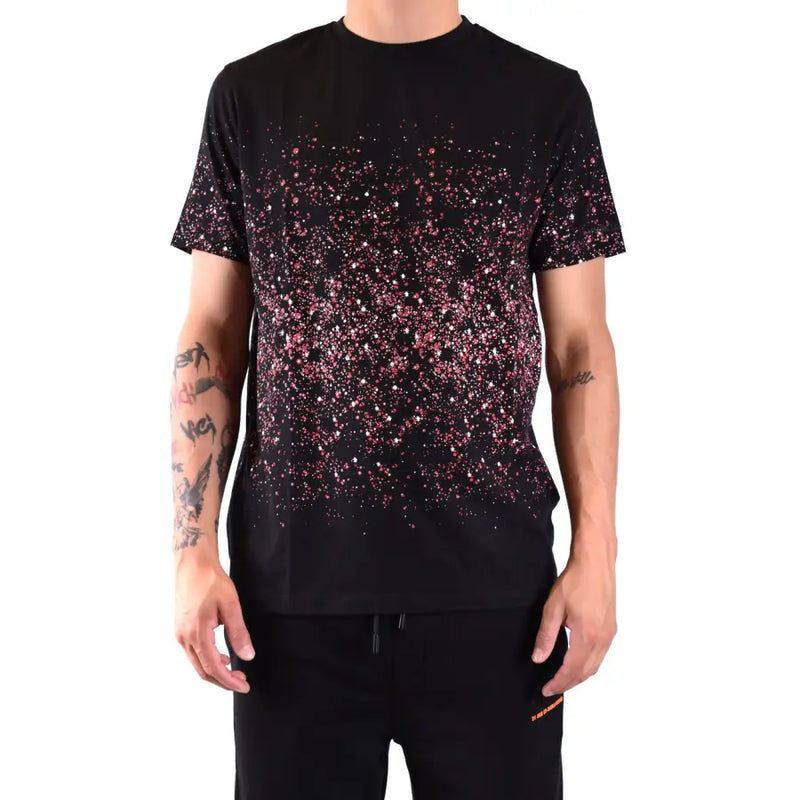 Schwarzes Kurzarm-T-Shirt mit rosa und weißen Glitzerpunkten, die von der Brust bis zum Saum in einem Spritzmuster auslaufen.