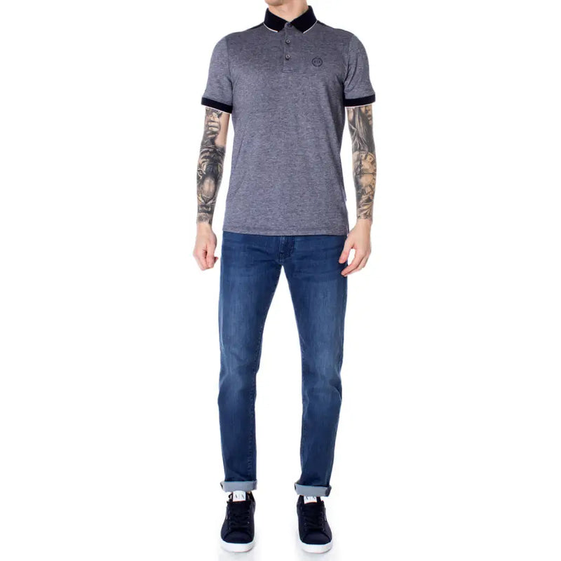 Grau-schwarzes Poloshirt mit kontrastierenden Ziernähten, schmal geschnittene Jeans, dunkelblaue Sneaker.