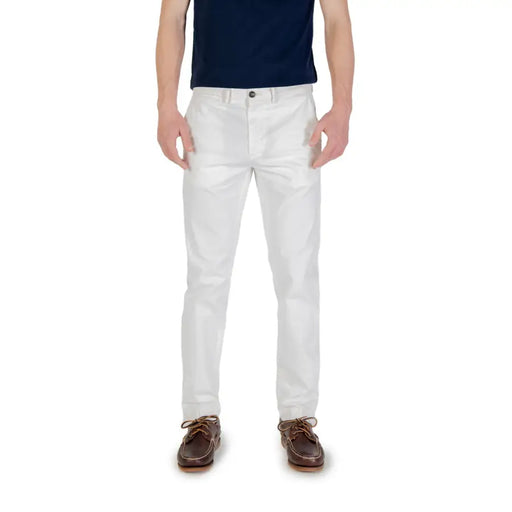 Men’s white chino pants paired with a dark blue t-shirt and brown boat shoes