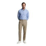 Ein Mann trägt eine Borghese Herrenhose aus kamelfarbenem Leinen (100 %), kombiniert mit einem hellblauen Button-Down-Hemd – ein Frühlings-/Sommeroutfit.