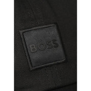 Schwarzer, strukturierter Stoffaufnäher mit geprägtem Boss-Logo auf dunklem, gewebtem Material der Boss Herrenkappe (100 % Baumwolle).