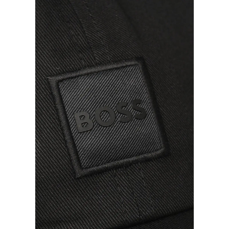 Schwarzer, strukturierter Stoffaufnäher mit geprägtem Boss-Logo auf dunklem, gewebtem Material der Boss Herrenkappe (100 % Baumwolle).