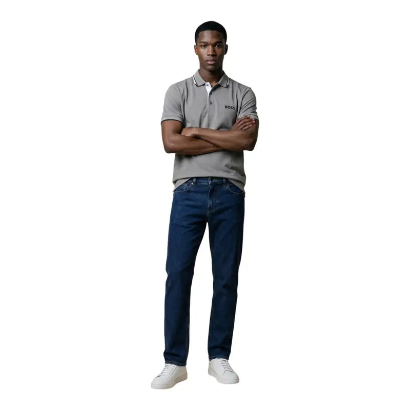 Ein Mann, der einen grauen Hugo Boss Kurzarm-Poloshirt aus Baumwollmischgewebe, kombiniert mit dunkelblauen Jeans in Größe L
