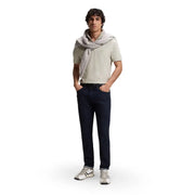 Ein Mann trägt ein graues, kurzärmeliges Poloshirt von Boss Men aus Baumwolle mit Reißverschluss am Kragen, dazu eine schmal geschnittene, dunkelblaue Jeans und weiße Sneaker.