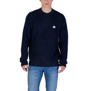 Navy blue crewneck sweater with small white logo on chest, made of cotton.