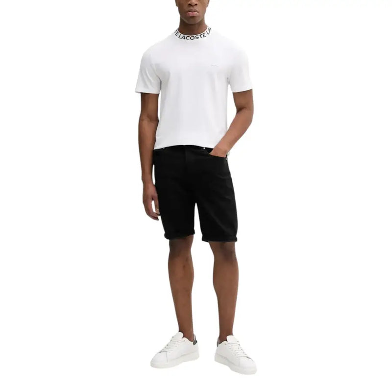 Weißes Lacoste-Poloshirt mit schwarzen Shorts und weißen Sneakers.