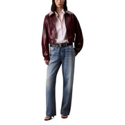 Woman wearing Bordeaux long zip front blazer with white shirt and wide-leg blue jeans