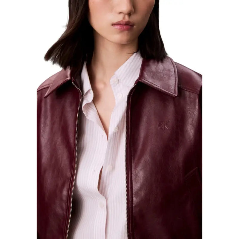 Woman wearing a burgundy leather bomber jacket over a white striped shirt showcasing Calvin Klein Jeans Bordeaux blazer