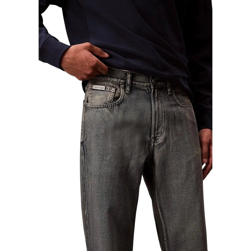 Back side of dark gray denim Calvin Klein jeans with faded wash and visible stitching in cotton blend fabric