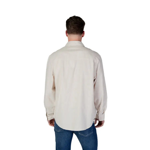 Men’s beige cotton long-sleeved button-down shirt paired with blue jeans in Calvin Klein Jeans collection