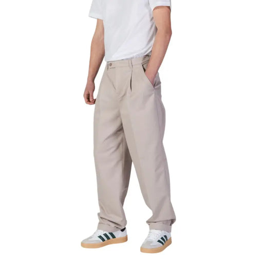 Men’s beige pleated trousers paired with white and green striped sneakers from Calvin Klein Jeans
